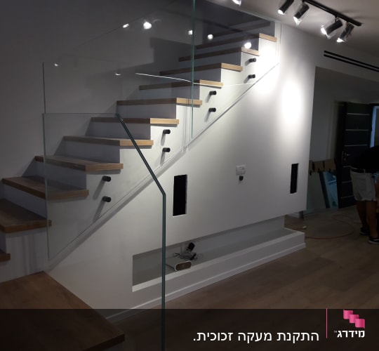 מעקה זכוכית שקוף לאורך גרם מדרגות עץ